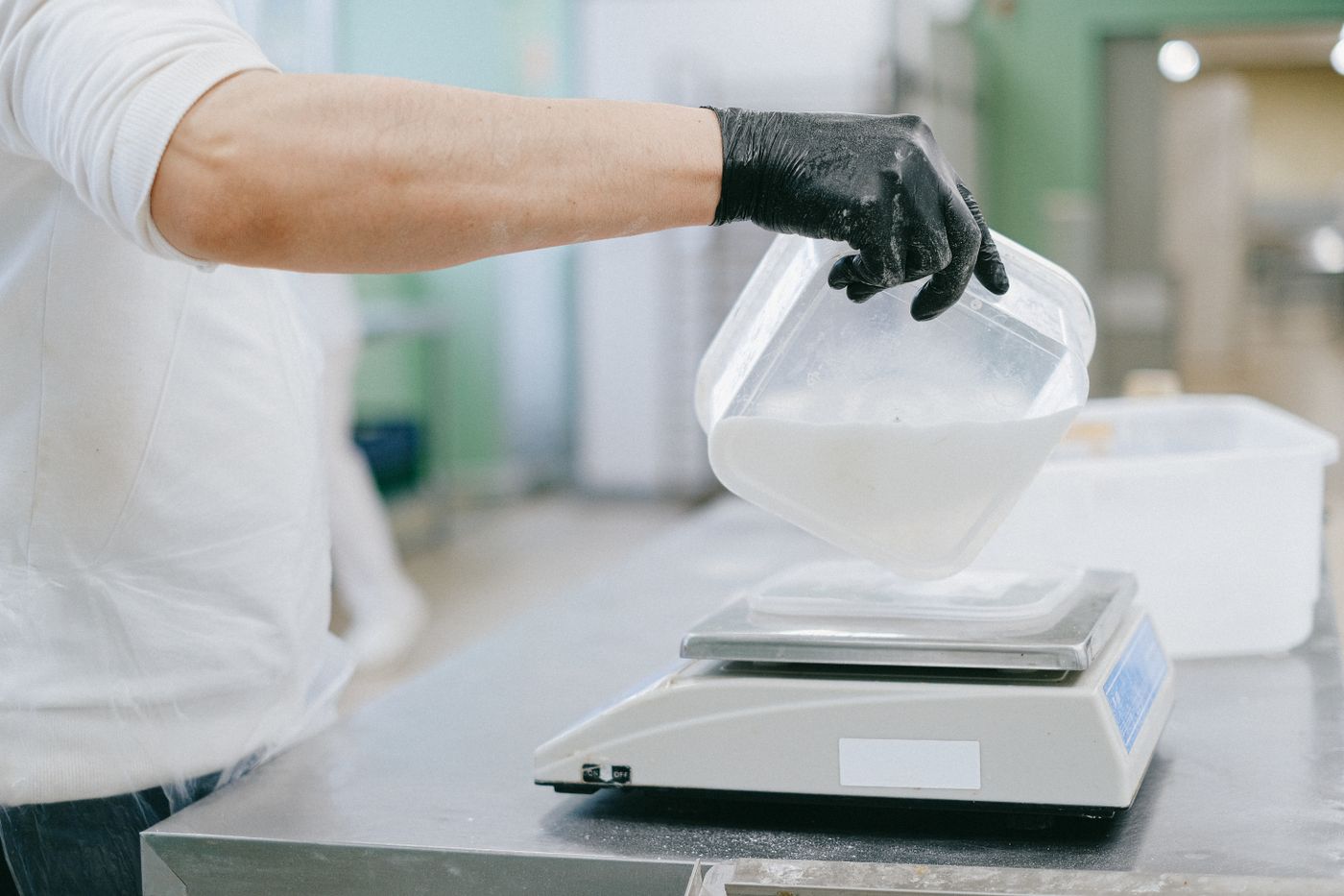 A cook weighing an ingredient on a commercial kitchen scale, the portion control that decides most inventory variance